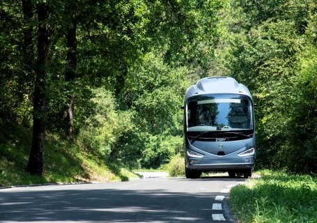 Grey coach travelling along the road in the countryside