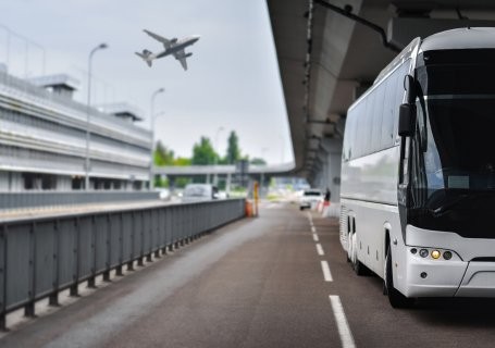 White coach on the road with an aeroplane above