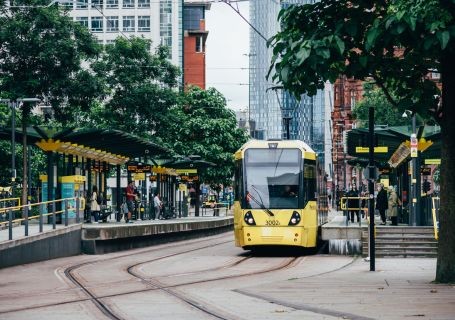 A bright yellow tram travelling through the urban paradise of Manchester