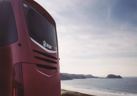 The bac of a red coach with a water landscape in the background